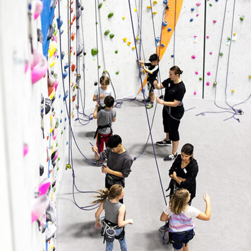 Large group of people in front of a climbing wall