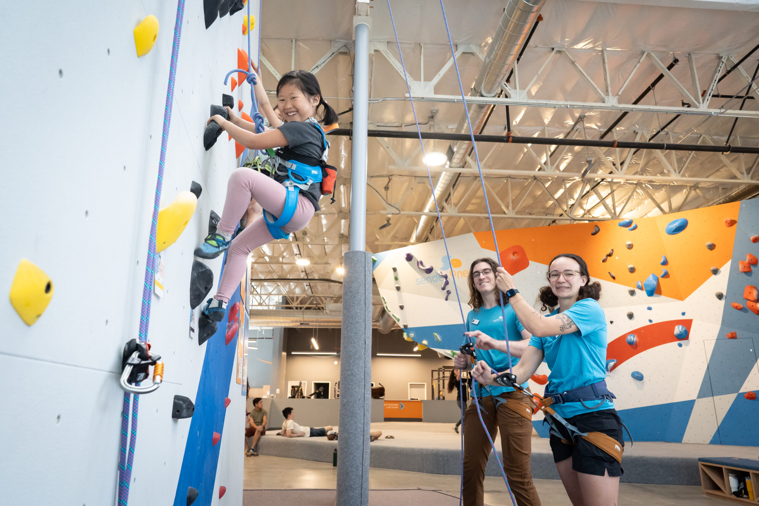 Employees assisting youth rope climb