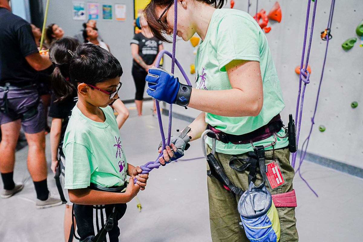 Staff helping young climber attach to climbing rope